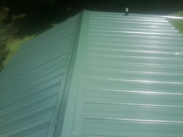 New green metal panels meeting at the ridge of a roof — Flat Roof Repair work by our crew in Hornbeak