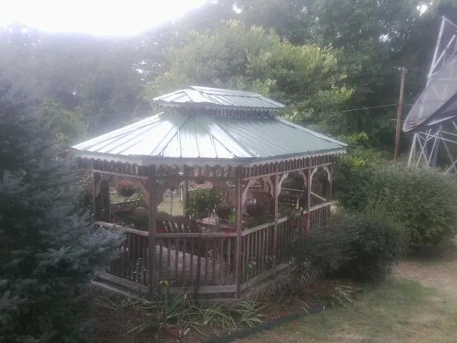 Green metal roof on a backyard gazebo surrounded by garden beds in Hornbeak
