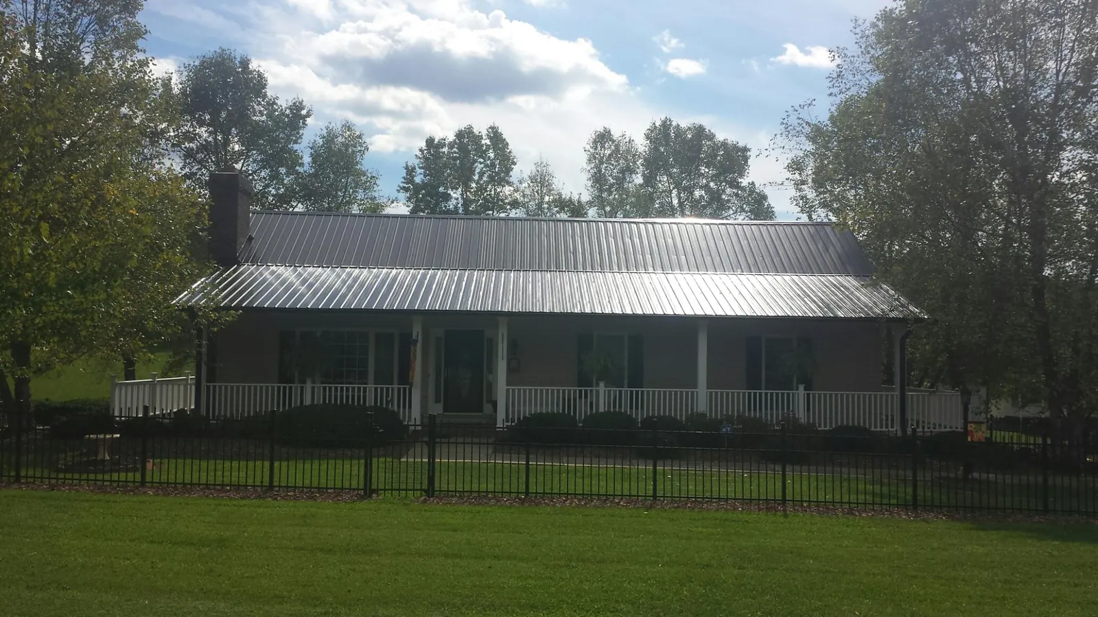 Gray metal roof on a brick ranch with a full width front porch — Gutter Guard Installation work by our crew in Hornbeak