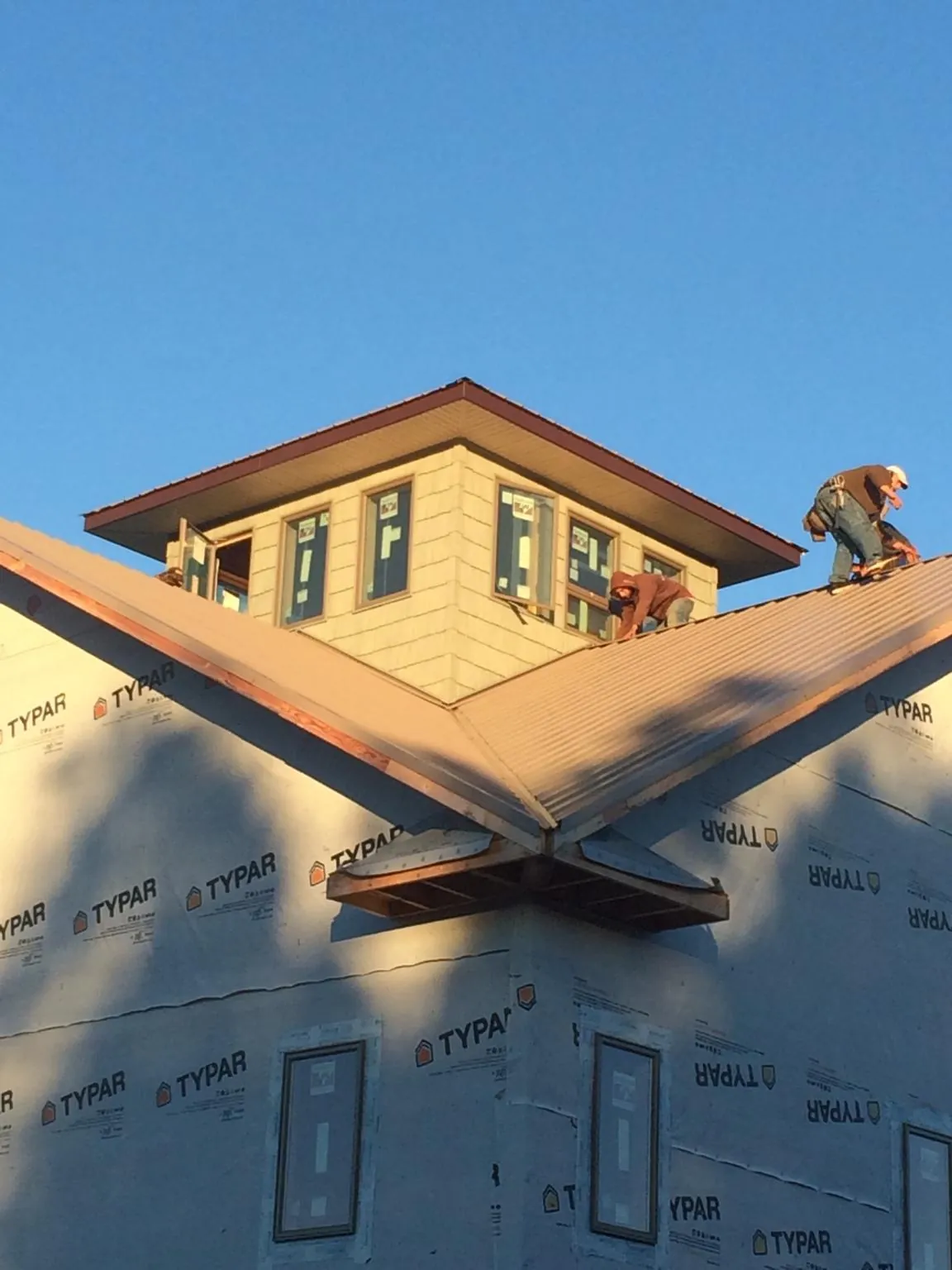 Roofers working around a rooftop cupola on a new metal roof at sunset — Roof Waterproofing in Hornbeak by Roofing Brothers